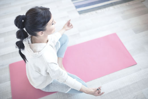 Woman doing yoga on a pink matt