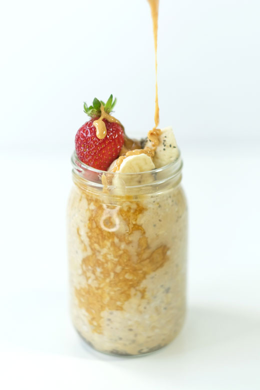 peanut butter being poured on top of overnight oats